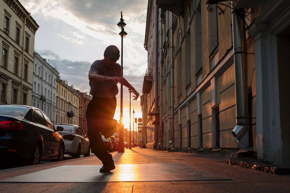 Dynamic street dancer moving creatively on a city street at sunset.